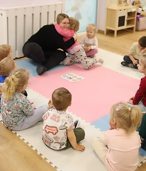 zdjęcie przedstawia opiekunkę i dzieci podczas zajęć